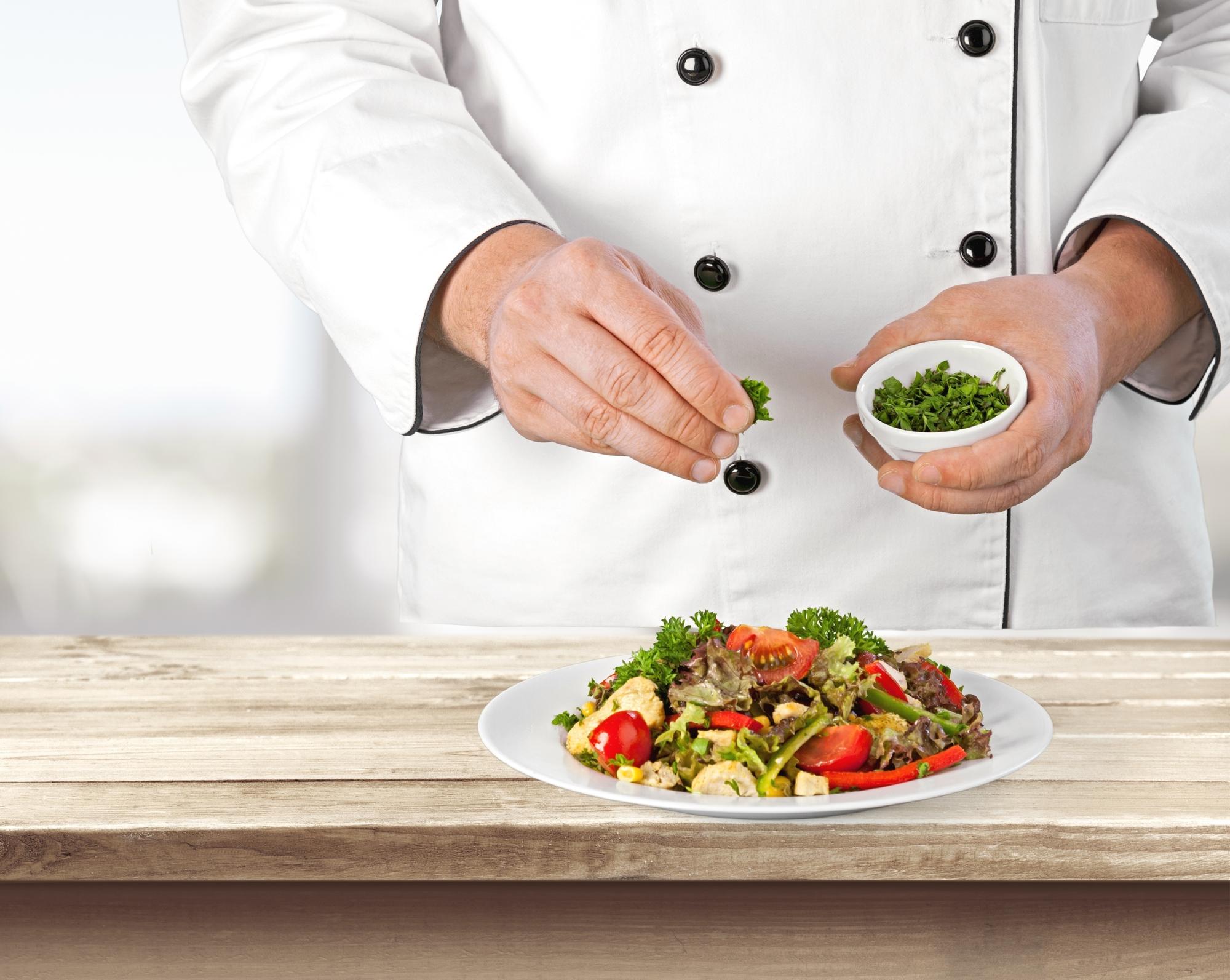 Instructor plating a seasonal salad on a wooden table
